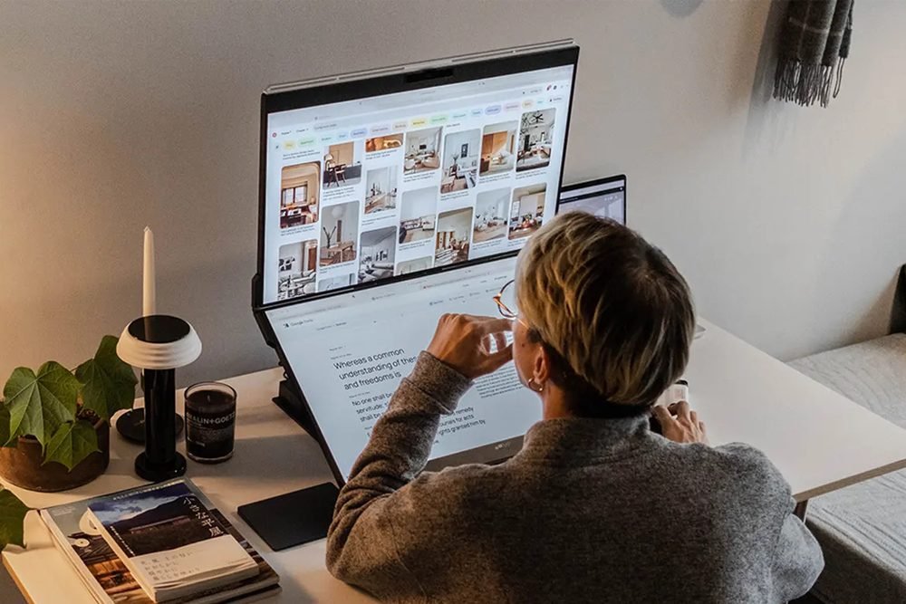 man in studio at desk with a double external screen for his laptop.