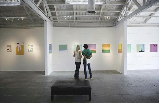 A couple in an art gallery checking out art collection on the wall