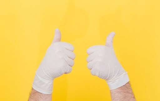 man holding up two thumbs in plastic surgeon gloves