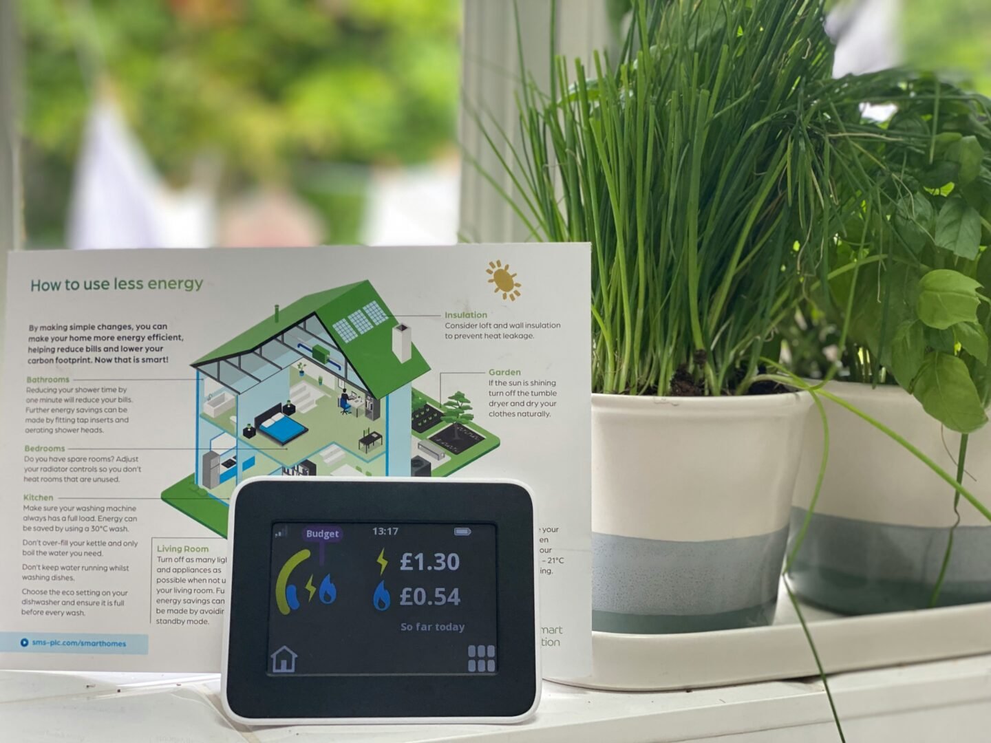 Smart energy meter display with energy-saving guide and potted herbs on windowsill